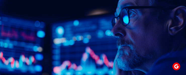 A man in glasses analyzes stock market graphs on a screen, focusing on important regulations for forex trading.