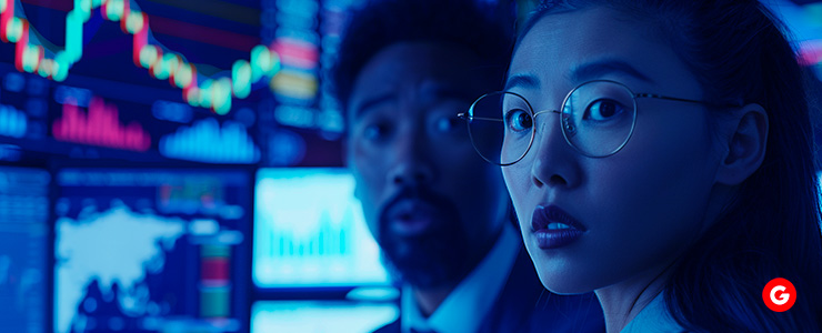 A woman and man analyzing stock market data on a screen.