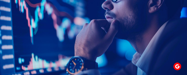 A man in a suit intently looking at a computer monitor displaying MetaTrader 4 (MT4) trading platform charts and financial data.