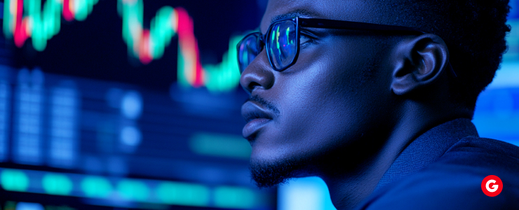 A bespectacled man studies stock market charts, focusing on trends and data for investment decisions.